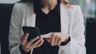 Ofiste akıllı telefon kullanan bir kadın.