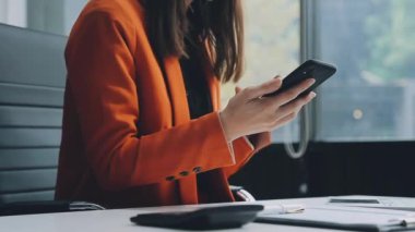 İş kadını ofiste çalışırken akıllı telefon kullanıyor.