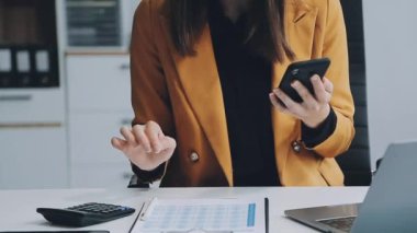 Ofiste hesap makinesi kullanan genç bir kadın..