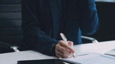 Genç işadamı ofiste çalışıyor, masada oturuyor.