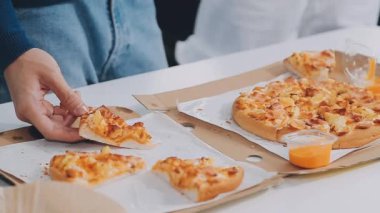 Bir kafede arka planda bulanık bir pizzayı tutan kişinin yakın plan fotoğrafı.