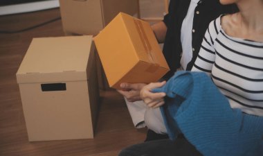 İki Asyalı blogcu, dükkanında canlı yayın yapan videoyu kaydetmek için kameranın önünde kıyafetlerini gösteriyor. Çevrimiçi alışveriş arabası fikri. Evdeki kanepede.