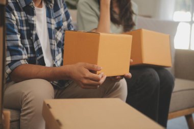 İki Asyalı blogcu, dükkanında canlı yayın yapan videoyu kaydetmek için kameranın önünde kıyafetlerini gösteriyor. Çevrimiçi alışveriş arabası fikri. Evdeki kanepede.