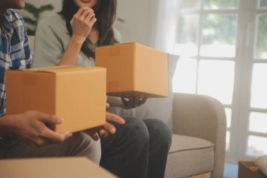 İki Asyalı blogcu, dükkanında canlı yayın yapan videoyu kaydetmek için kameranın önünde kıyafetlerini gösteriyor. Çevrimiçi alışveriş arabası fikri. Evdeki kanepede.