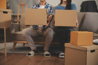 İki Asyalı blogcu, dükkanında canlı yayın yapan videoyu kaydetmek için kameranın önünde kıyafetlerini gösteriyor. Çevrimiçi alışveriş arabası fikri. Evdeki kanepede.