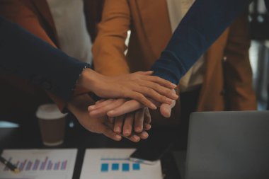 Genç Asyalı girişimciler ve girişimciler iş toplantısı yapıyorlar ve başarılı pazarlama planı konseptini gerçekleştirmek için ruhsal enerji için birbirlerini teşvik ediyorlar.