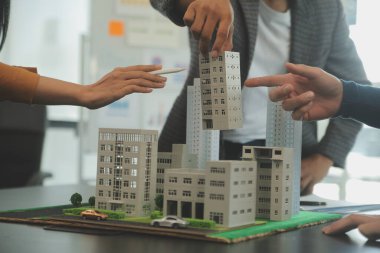 Mimarlar ve iş adamları, emlak yatırımları ve konut geliştirme projesi için zemin planı modifikasyonunu tartışıp fikir alışverişinde bulunuyorlar.