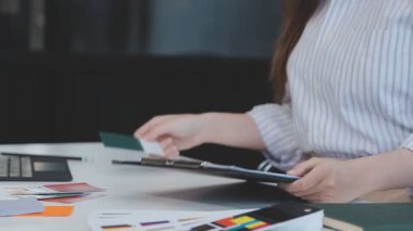 Genç bir iş kadını, iş ve finans kavramlarını ön plana çıkaran bir fon ile çağdaş bir ofiste çalışırken resmedilir..