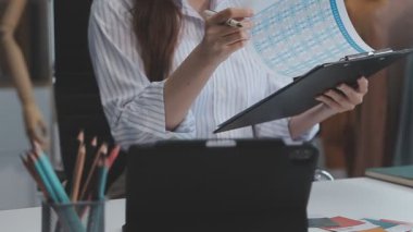 Genç bir iş kadını, iş ve finans kavramlarını ön plana çıkaran bir fon ile çağdaş bir ofiste çalışırken resmedilir..