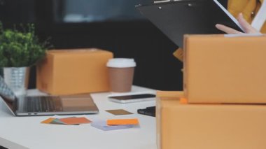 Dizüstü bilgisayarı ve elinde karton kutusuyla genç bir kadın. Online alışveriş kavramı.