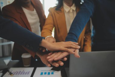 Genç Asyalı girişimciler ve girişimciler iş toplantısı yapıyorlar ve başarılı pazarlama planı konseptini gerçekleştirmek için ruhsal enerji için birbirlerini teşvik ediyorlar.