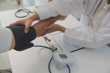 Erkek doktor, check-up, tıbbi tedavi ve sağlık konsepti için hastaneye gelen hastaların vücut basıncını ve nabzını ölçmek için kan basıncı monitörü kullanır..