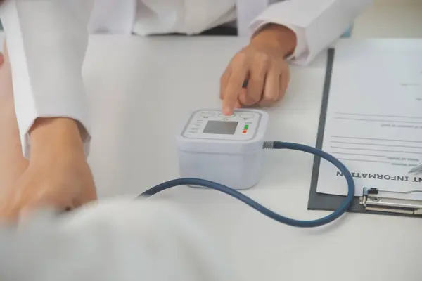 Erkek doktor, check-up, tıbbi tedavi ve sağlık konsepti için hastaneye gelen hastaların vücut basıncını ve nabzını ölçmek için kan basıncı monitörü kullanır..