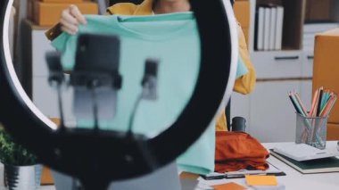 Genç Asyalı kadın video yayını, moda blogcusu ve çevrimiçi iş konseptiyle ürünler satıyor 
