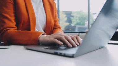 Ofiste dizüstü bilgisayarda oturan yakışıklı Asyalı iş kadını Milli Gelir İdaresi 'nin belgelerini kontrol ederek rapor hazırlıyor..