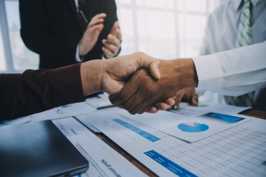 Emlakçı ve müşteriler el sıkışıyor. Ev sigortası, yatırım kredisi, tokalaşma ve başarılı anlaşmayla ilgili bitirilen sözleşmeyi kutluyorlar..