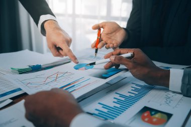 İş fikri. İş adamları konuşuyor ve başarılı takım çalışmalarının yatırım sonuçlarının büyümesini gösteren grafikler ve grafikler hakkında hesaplamalar yapıyorlar.