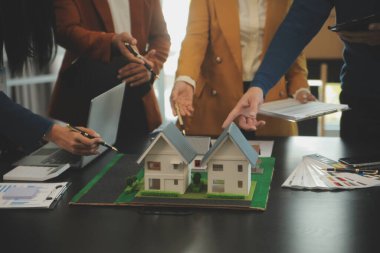 Mimarlar ve iş adamları, emlak yatırımları ve konut geliştirme projesi için zemin planı modifikasyonunu tartışıp fikir alışverişinde bulunuyorlar.