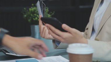 İş kadını cep telefonu kullanıyor ve kafede kredi kartı tutuyor, alışveriş konsepti, akıllı telefon kullanarak işadamına yakın çekim
