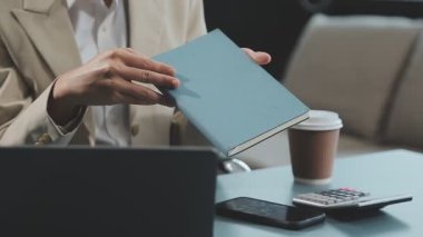 Bir kafede dizüstü bilgisayar ve belgelerle çalışan bir iş adamı.