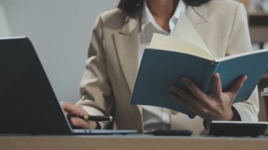 İş kadını ofiste bir belgeyi okurken kitap okuyor