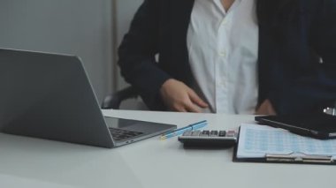 Genç işadamı ofis masasında dizüstü bilgisayar ve belgelerle çalışıyor..