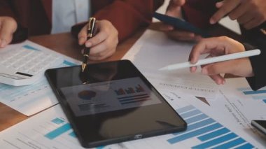 Genç iş adamları toplantı odasında dijital tablet verilerini tartışıyor ve analiz ediyorlar.