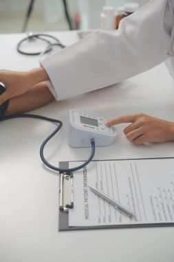 Erkek doktor, check-up, tıbbi tedavi ve sağlık konsepti için hastaneye gelen hastaların vücut basıncını ve nabzını ölçmek için kan basıncı monitörü kullanır..