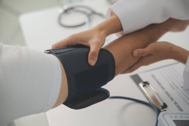 Erkek doktor, check-up, tıbbi tedavi ve sağlık konsepti için hastaneye gelen hastaların vücut basıncını ve nabzını ölçmek için kan basıncı monitörü kullanır..