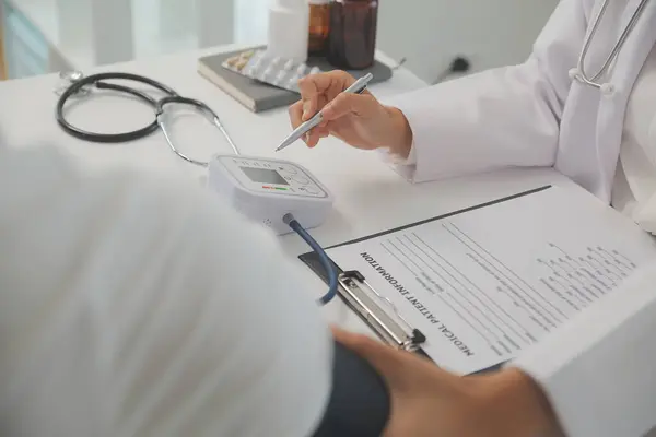 Erkek doktor, check-up, tıbbi tedavi ve sağlık konsepti için hastaneye gelen hastaların vücut basıncını ve nabzını ölçmek için kan basıncı monitörü kullanır..