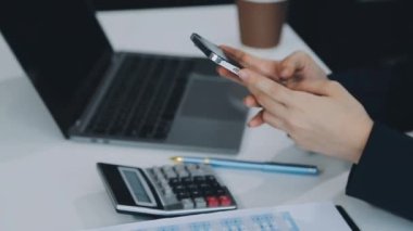 Ofiste akıllı telefon ve dizüstü bilgisayarla çalışan iş kadını.