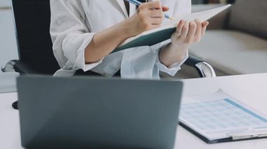 Beyaz önlüklü kadın belgelerle çalışıyor.