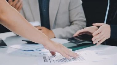 Bir belgeyi elinde tutan ve ofisteki toplantıya parmağıyla işaret eden işadamının yakın görüntüsü..
