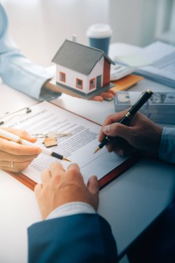 Emlakçı ev satın alma anlaşmasının şartları hakkında konuştu ve müşteriden sözleşmeyi yasal hale getirmek için belgeleri imzalamasını istedi, ev satışları ve ev sigortası kavramı.