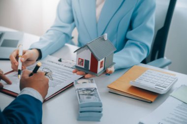 Emlakçı ev satın alma anlaşmasının şartları hakkında konuştu ve müşteriden sözleşmeyi yasal hale getirmek için belgeleri imzalamasını istedi, ev satışları ve ev sigortası kavramı.