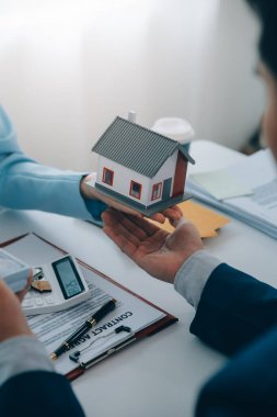 Emlakçı ev satın alma anlaşmasının şartları hakkında konuştu ve müşteriden sözleşmeyi yasal hale getirmek için belgeleri imzalamasını istedi, ev satışları ve ev sigortası kavramı.