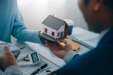 Emlakçı ev satın alma anlaşmasının şartları hakkında konuştu ve müşteriden sözleşmeyi yasal hale getirmek için belgeleri imzalamasını istedi, ev satışları ve ev sigortası kavramı.