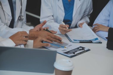 Sağlık personeli sabah toplantı odasında toplanıyor. Dijital tablete bakan doktorlar ve hemşireler.