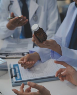 Sağlık personeli sabah toplantı odasında toplanıyor. Dijital tablete bakan doktorlar ve hemşireler.