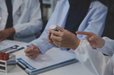 Sağlık personeli sabah toplantı odasında toplanıyor. Dijital tablete bakan doktorlar ve hemşireler.