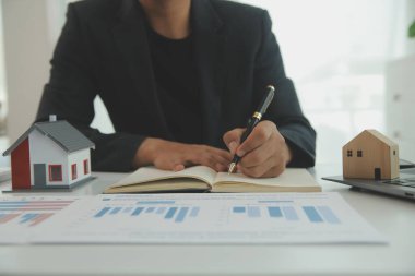 Businessmen holding pens, signing home titles with insurance, care about real estate services and the idea of real estate agents offering interest in installments to their customers.