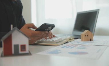 Businessmen holding pens, signing home titles with insurance, care about real estate services and the idea of real estate agents offering interest in installments to their customers.