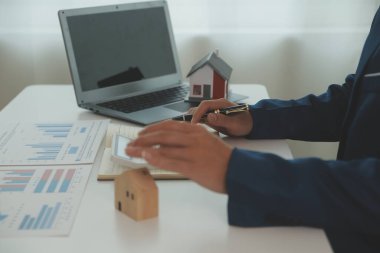 Businessmen holding pens, signing home titles with insurance, care about real estate services and the idea of real estate agents offering interest in installments to their customers.