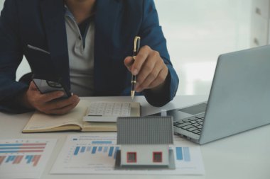 Businessmen holding pens, signing home titles with insurance, care about real estate services and the idea of real estate agents offering interest in installments to their customers.