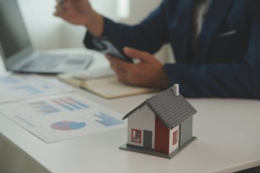 Businessmen holding pens, signing home titles with insurance, care about real estate services and the idea of real estate agents offering interest in installments to their customers.