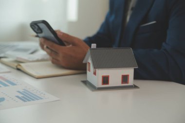 Businessmen holding pens, signing home titles with insurance, care about real estate services and the idea of real estate agents offering interest in installments to their customers.