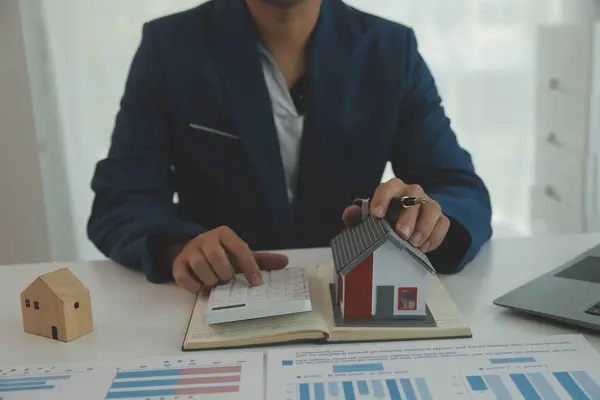 Businessmen holding pens, signing home titles with insurance, care about real estate services and the idea of real estate agents offering interest in installments to their customers.