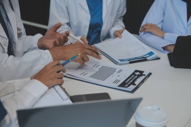 Sağlık personeli sabah toplantı odasında toplanıyor. Dijital tablete bakan doktorlar ve hemşireler.