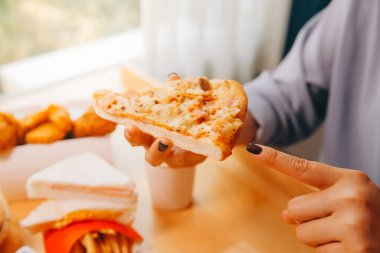 Restoranda pizza dilimi tutan bir kadın resmi.