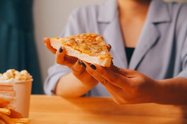 Restoranda pizza dilimi tutan bir kadın resmi.